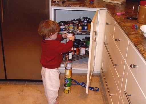 toddler standing by open cupboard