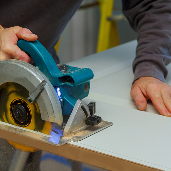 A man using a circular saw to cut a door to size