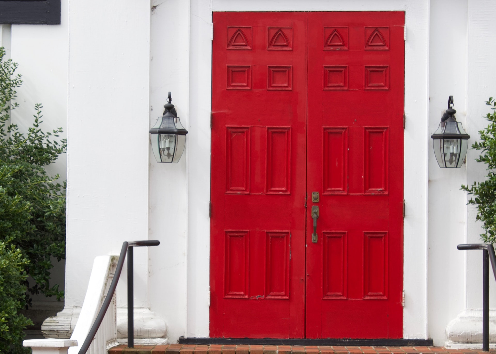 Red double external doors on a white house